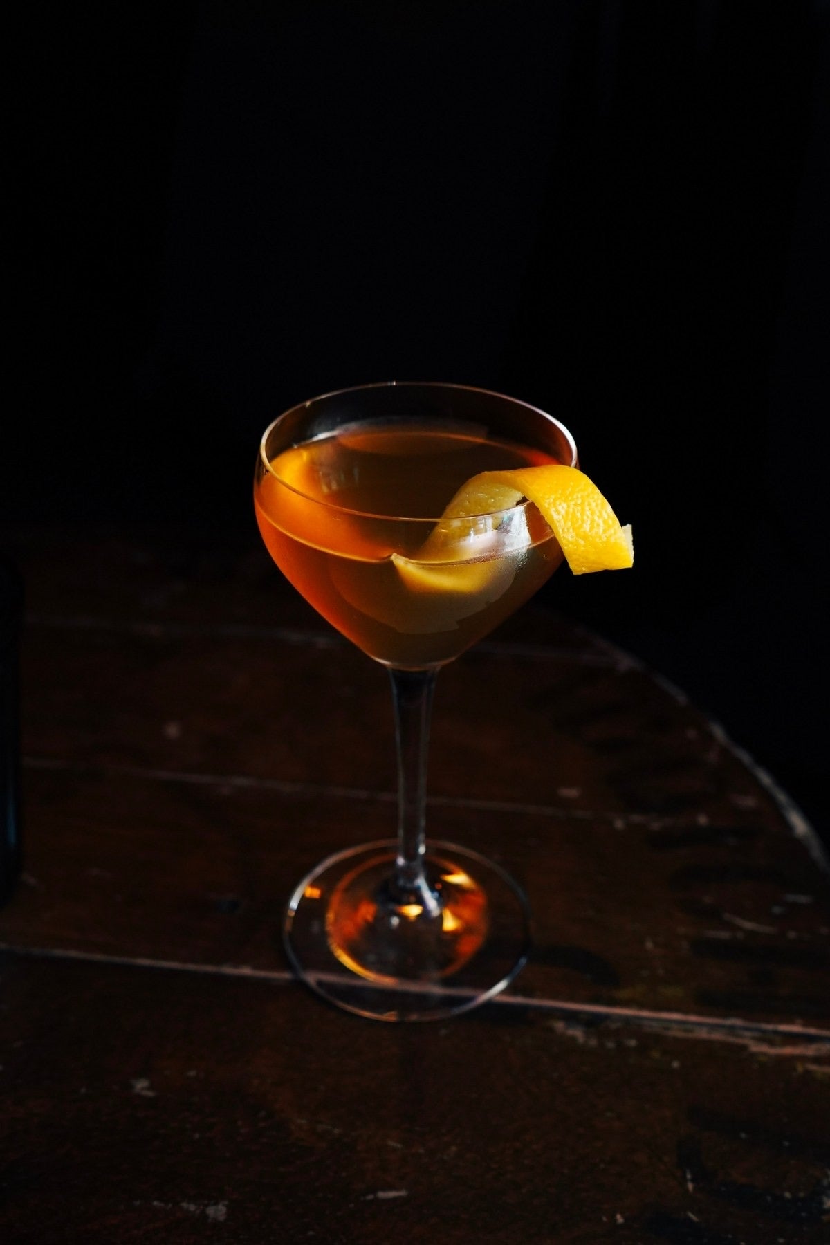 An amber cocktail with orange peel